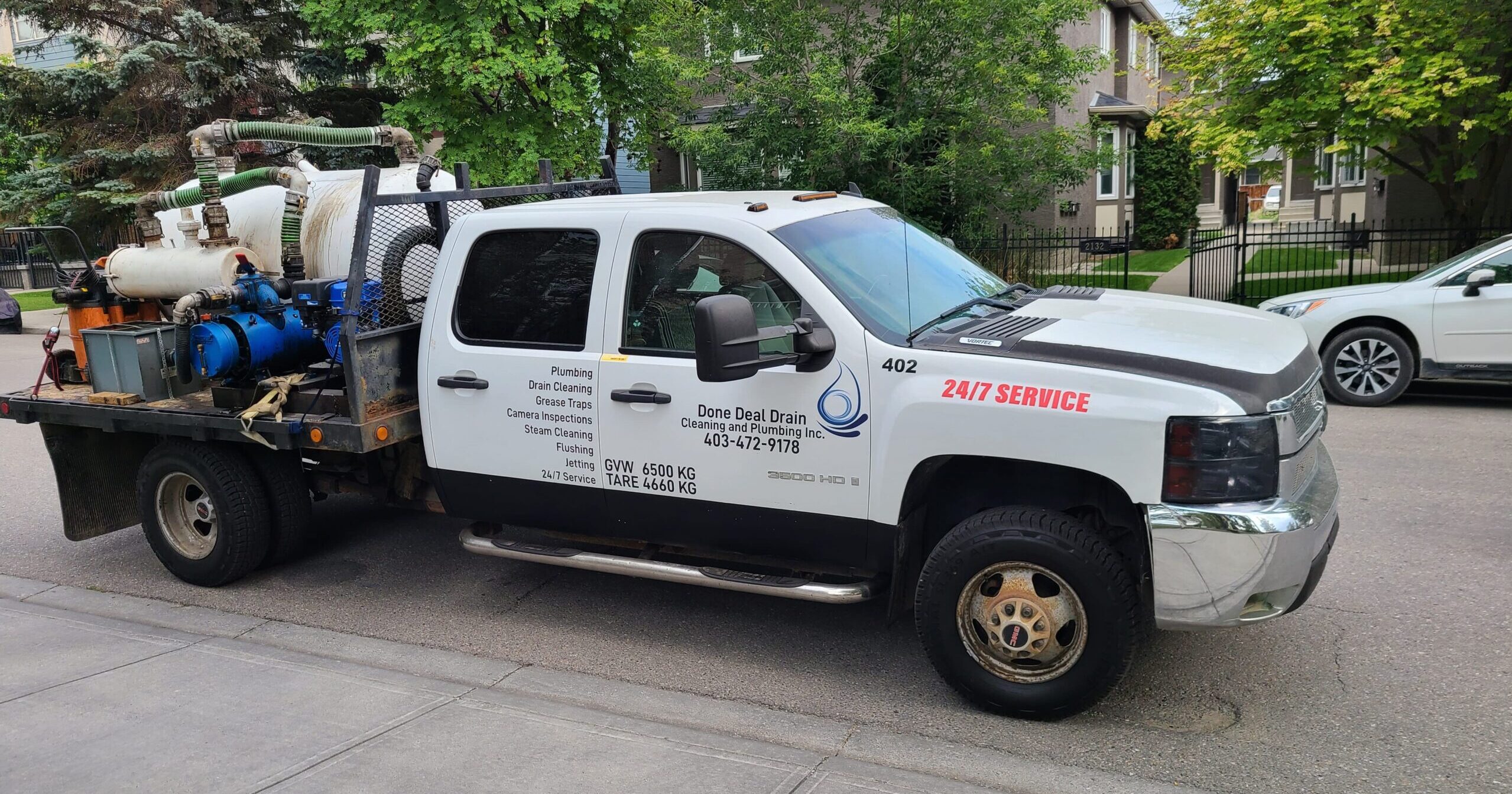 Done Deal Drain Cleaning & Plumbing service truck 402 with hydro-jetting and vacuum equipment, parked on a Calgary street